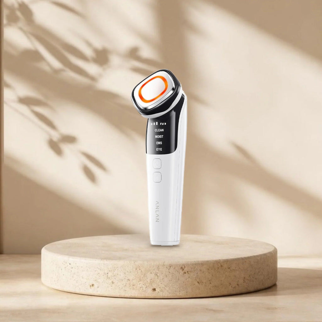 Appareil microcourant visage ANLAN 6 modes sur une plinthe en travertin, lumière naturelle et ombres de feuillage