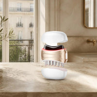 Gua sha électrique 2 en 1 ANLAN (tête en jade, peigne et capots) sur le plan de toilette d’une salle de bain parisienne lumineuse