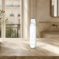 Spatule ultrasonique visage ANLAN blanche sur le plan de toilette d’une salle de bain parisienne lumineuse
