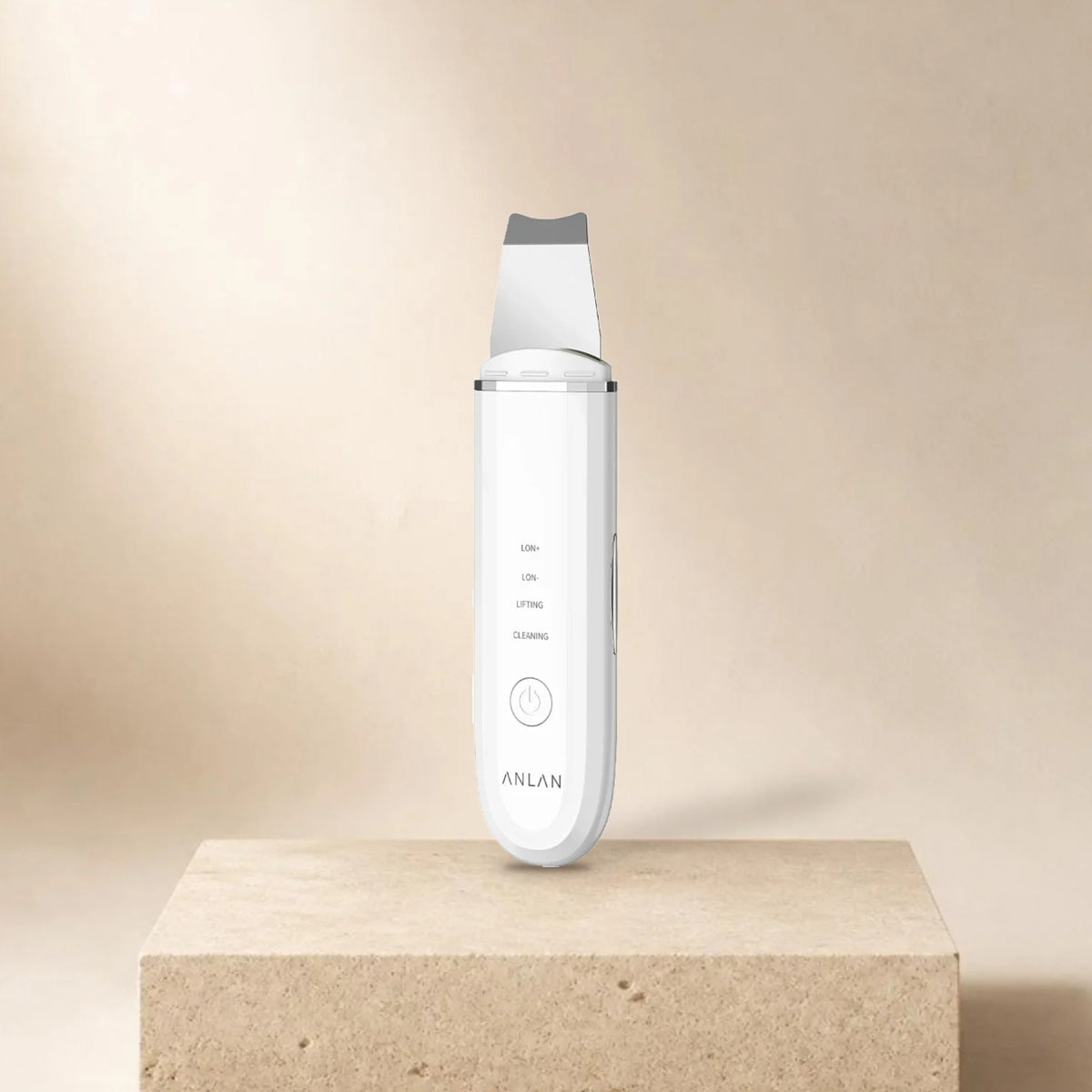 Spatule ultrasonique visage ANLAN blanche posée sur un socle en pierre, fond beige